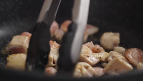 cocinero anónimo girando trozos de carne en la sartén