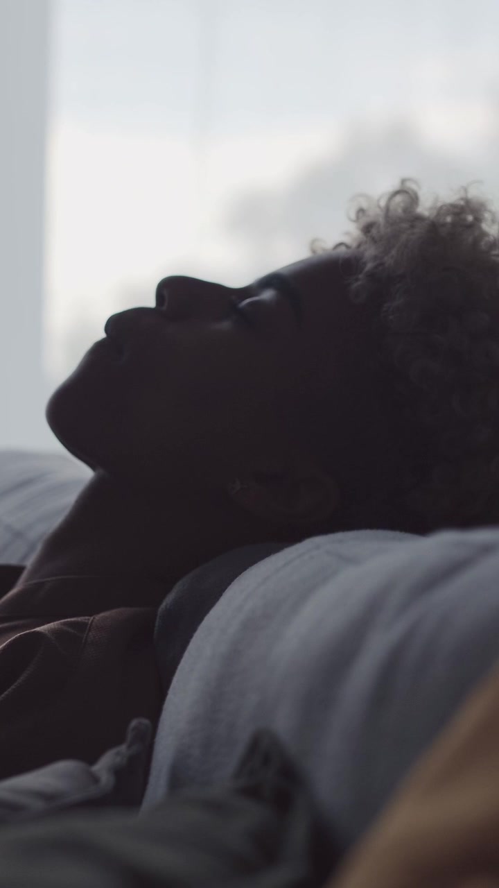 Silhueta de mulher afro-americana cansada, recostada para descansar no sofá.