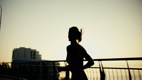 Rear-view-of-the-silhouette-of-a-sports-girl-who-is-jogging-in-the-morning.-Active-lifestyle