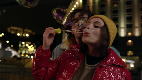 smiling couple blowing soap bubbles outdoor. pair enjoying date on urban street.