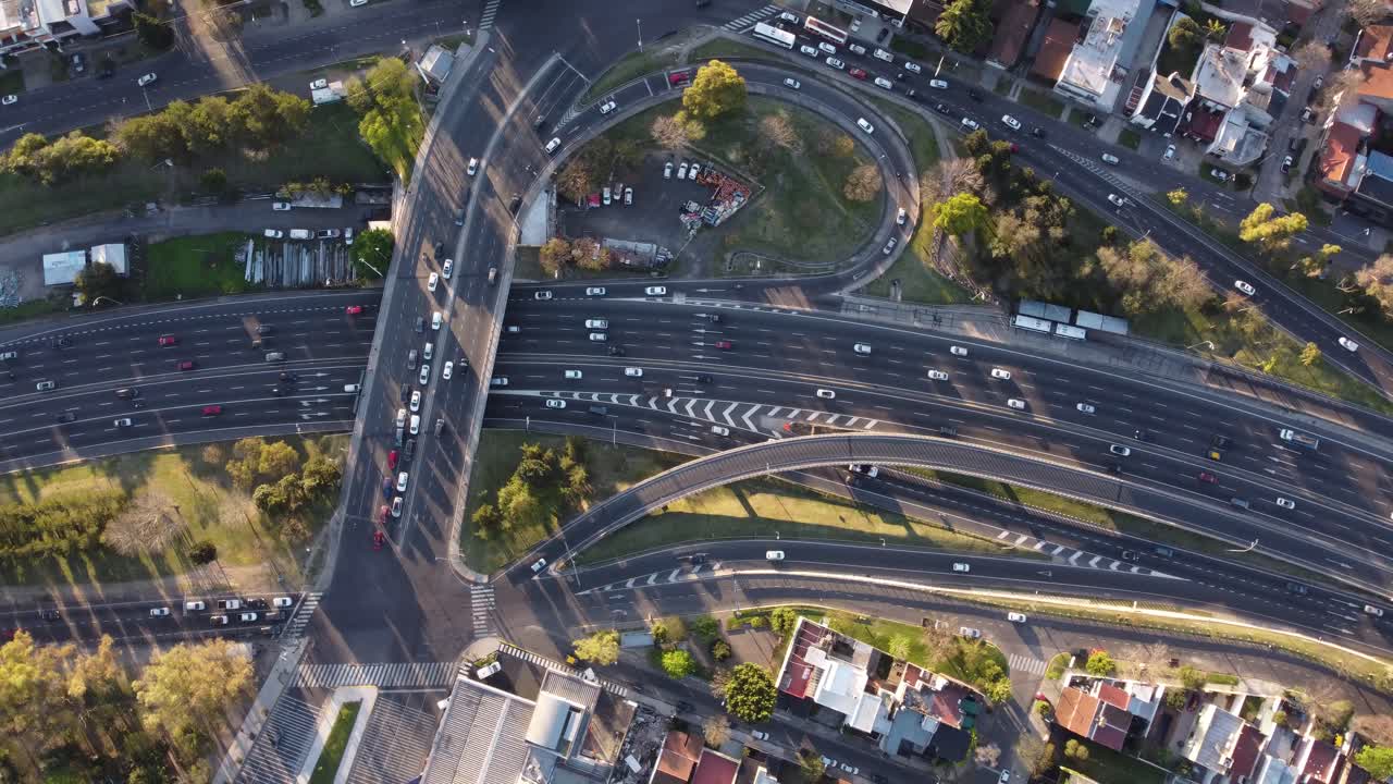 ángulo alto cinemático arriba hacia abajo del tráfico ocupado en la carretera panamericana, el puente y las salidas durante la puesta de sol - hermosa textura de los autos en movimiento - toma de órbita aérea