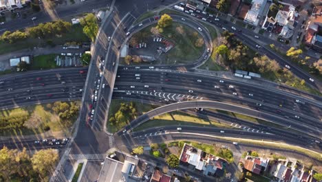 ángulo alto cinemático arriba hacia abajo del tráfico ocupado en la carretera panamericana, el puente y las salidas durante la puesta de sol - hermosa textura de los autos en movimiento - toma de órbita aérea