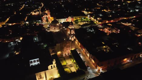 aerial orbit over the facade of the templo de san francisco de asis in san miguel de allende at night