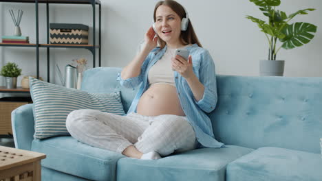 pregnant woman listening to music on couch