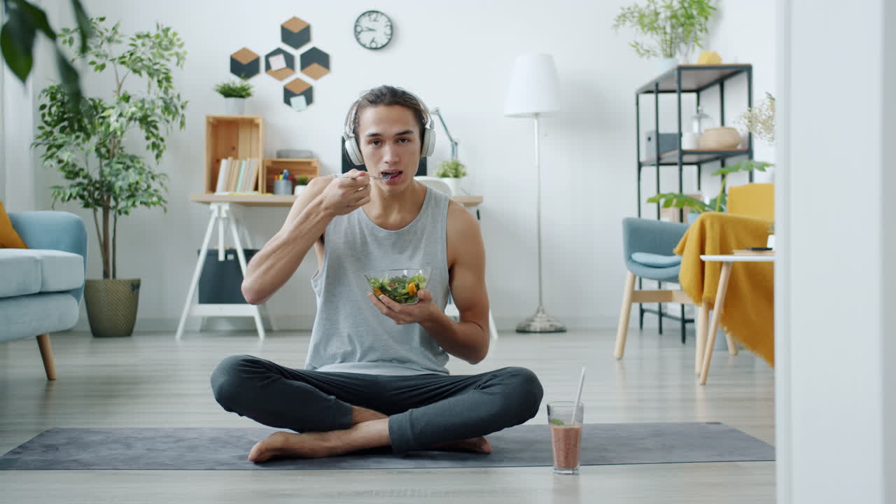 Man eating salad and listening to music while meditating at home