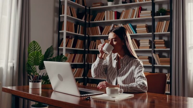 Kvinde arbejder på hjemmekontor med bærbar computer og kaffe