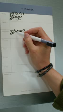 person writing on a weekly planner