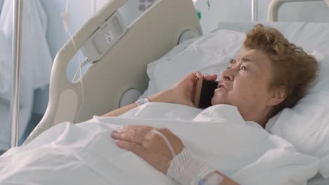 elderly female patient lying on the hospital bed and talking on her cellphone