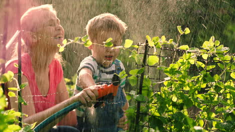 Madre-Ayudando-A-Su-Hijo-A-Regar-El-Jardín-Con-Una-Manguera