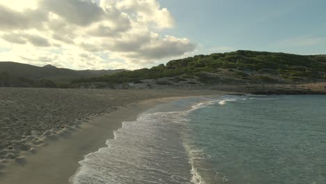 discover the tranquil shores of cala torta, a hidden gem in mallorca, where golden sands meet gentle waves and lush greenery rises in the background at sunset.