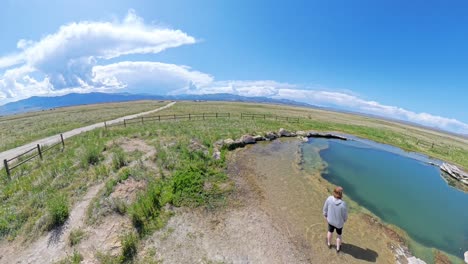 ultra wide angle of hot spring in utah with a red haired male wading in mineral water