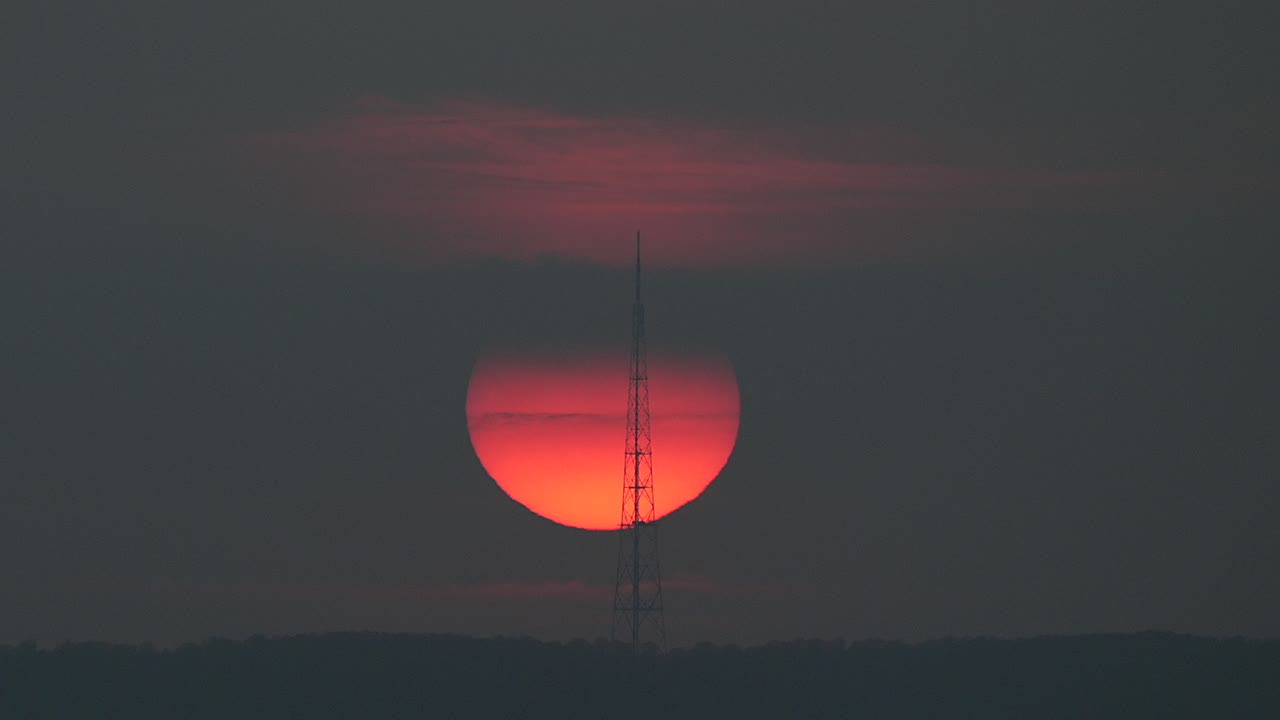 Sunset over a distant landscape time lapse, power transmission tower silhouette