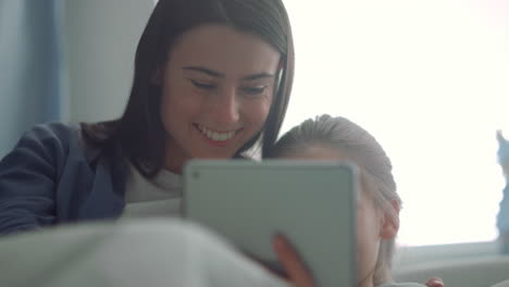 una madre sonriente escribiendo, abrazando a su hija de cerca, momentos de infancia despreocupados.