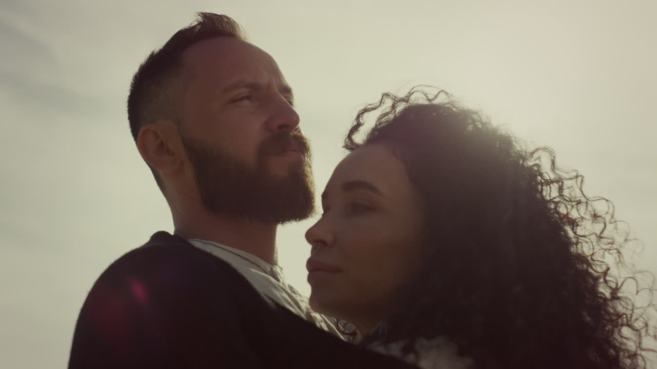 Romantic people face looking together. Two people enjoy wind blow on sunset sky.