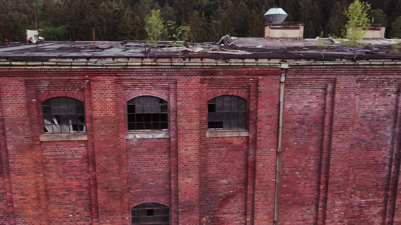 Drone flies horizontally to the left outside of a lost place socialist VEB Factory in eastern Germany at sundown