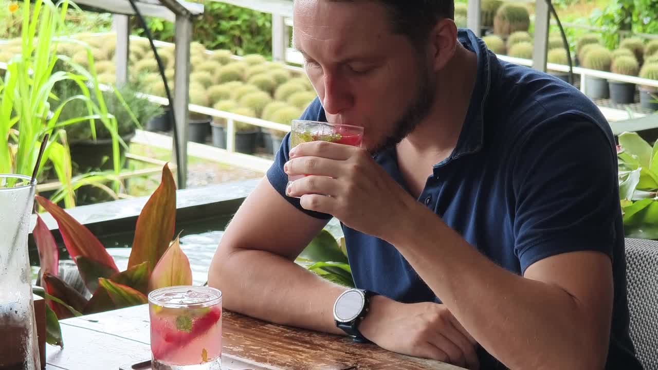 hombre disfrutando de un cóctel en un restaurante de jardín tropical