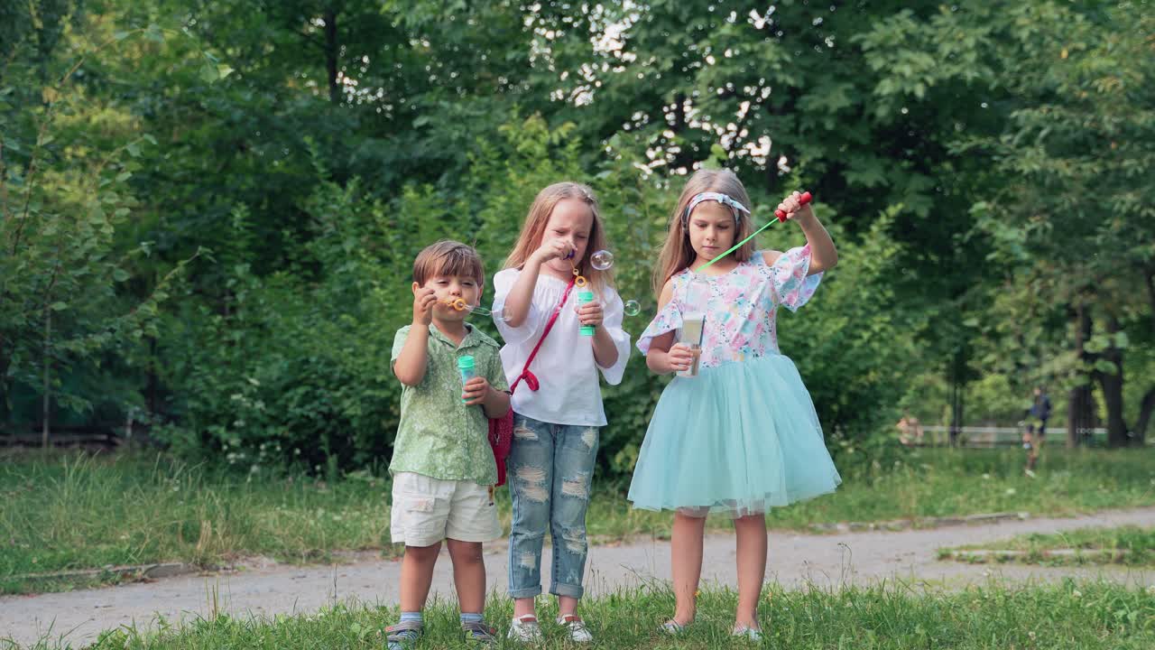 Soap bubbles from a bottle. Small children blow bubbles in the park. Boy and girls playing at a children's party