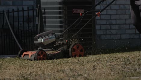 slow motion of an electric mower being pushed in a backyard