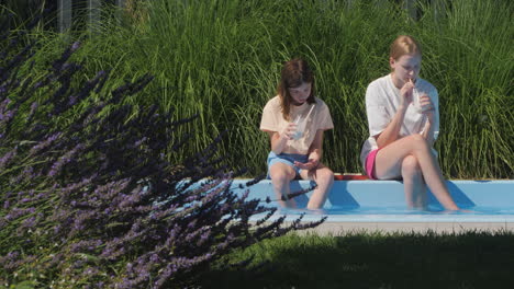 two girls enjoying a drink by the pool