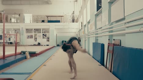 female athlete exercising in the gym running up and doing a double somersault back 3