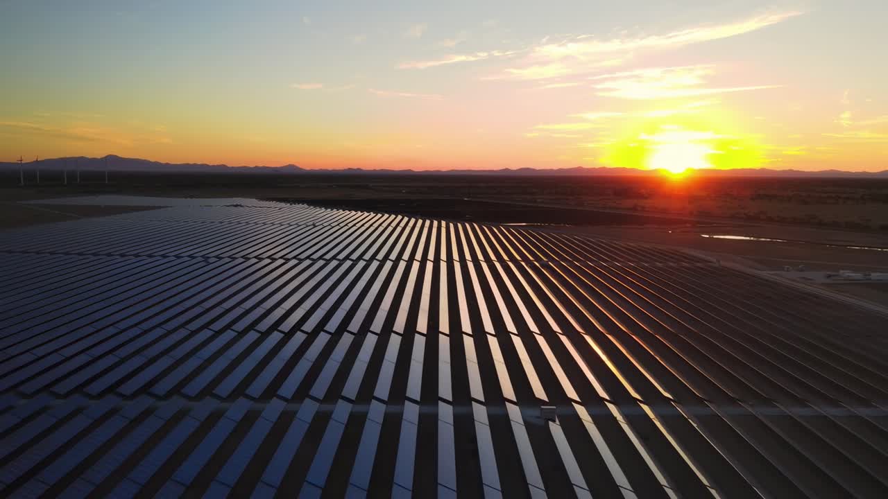Luftvideo af solpaneler ved solnedgang, der fanger konceptet om vedvarende energi med en vidvinkeludsigt.