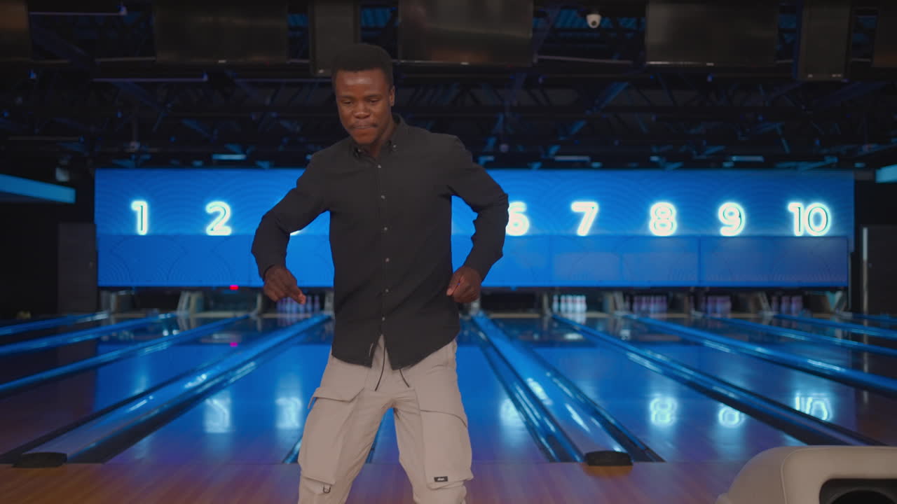 Black African-American man Jump happily looking at the camera celebrate the victory in slow motion. Throw in the bowling alley to make a shoot. Victory dance and jump with happiness.