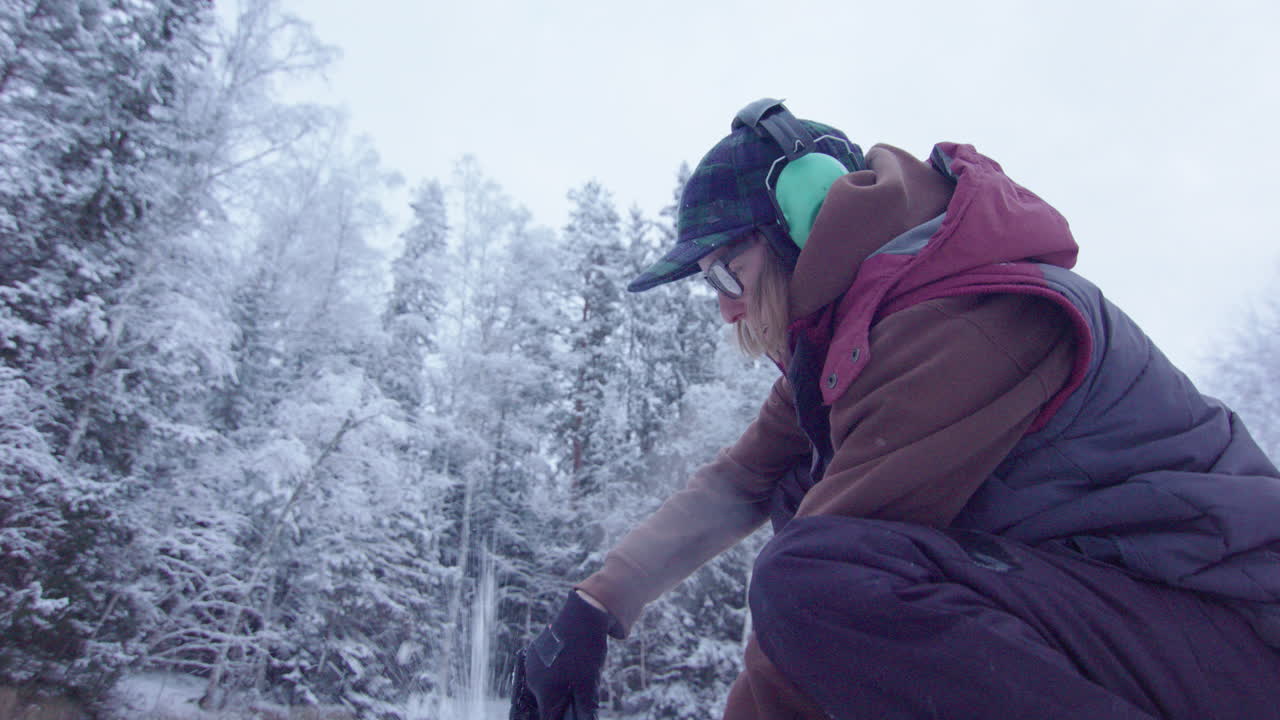핸드헬드 액션 - 전기톱으로 얼음 구멍을 뚫는 여성