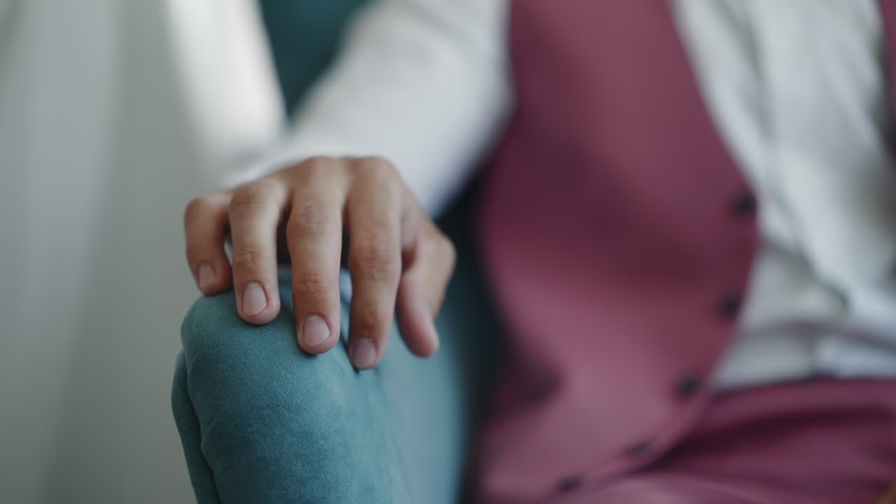 Ung mand i lilla jakkesæt med vest banker på gelænder ved lænestol.