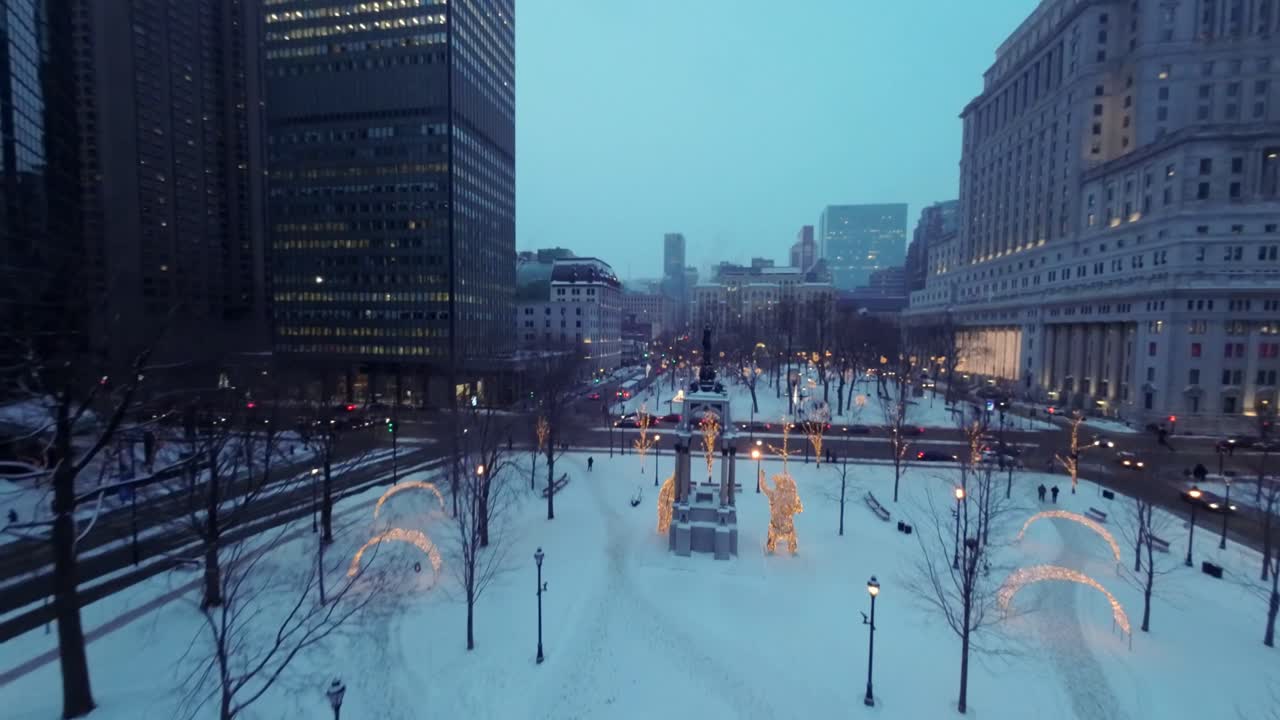 FPV drone glides over snowy Place du Canada adorned with Christmas decorations, heading toward René Lévesque Blvd W during peaceful winter morning at Square Dorchester, Downtown Montreal.