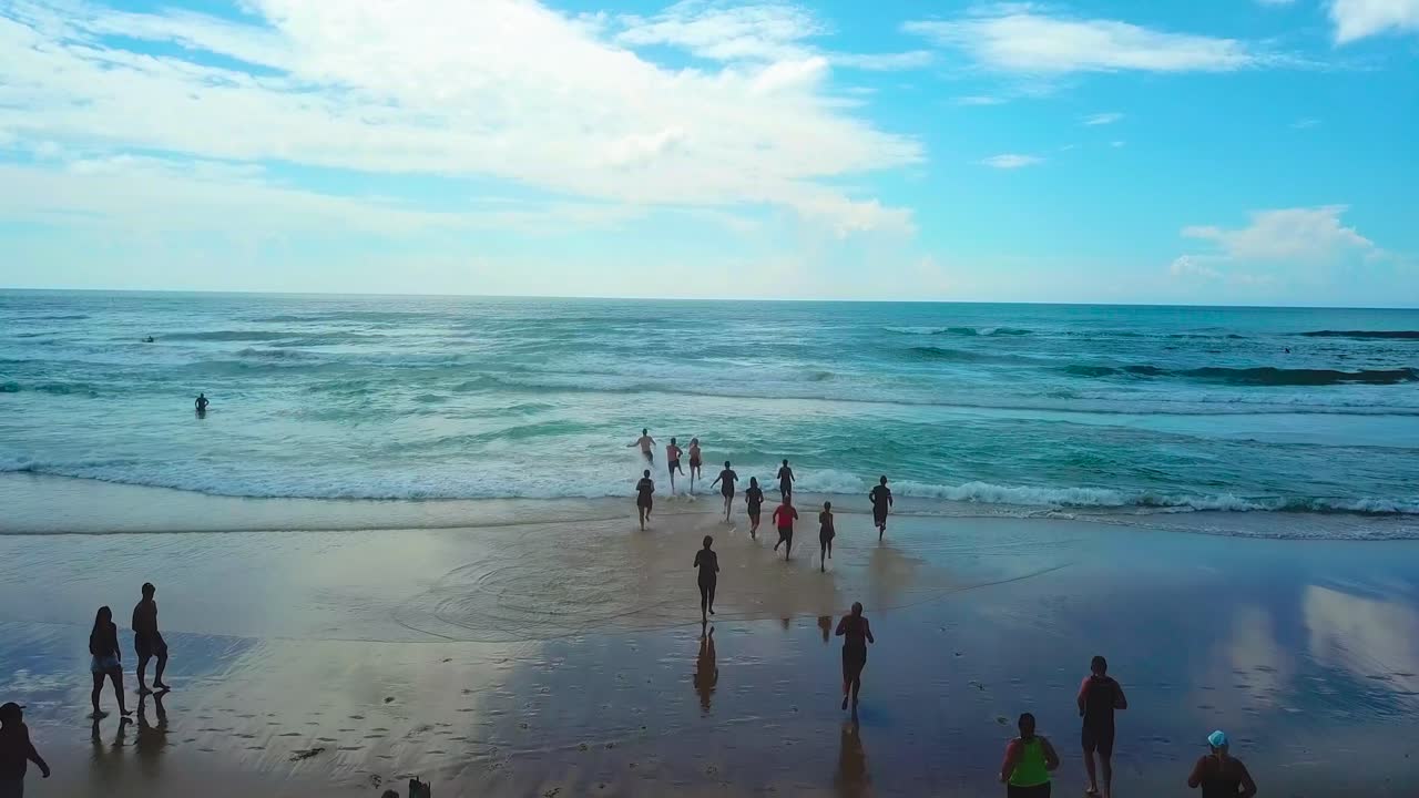 푸른 바다로 뛰어드는 해변과 사람들의 공중 추적 보기