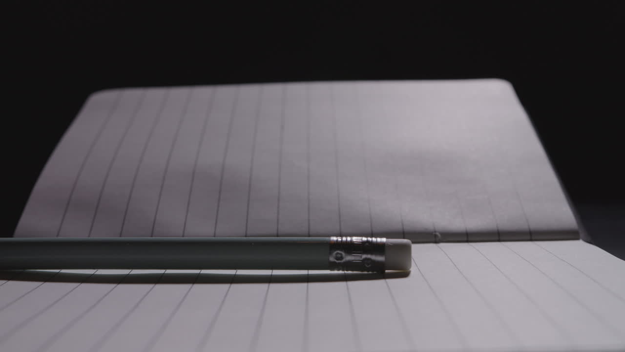 Close up of a pencil being laid down on an open notebook