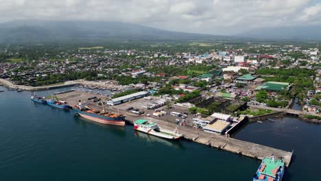 aerial view of tabaco port with cloud-capped mount mayon in distance. tabaco city, albay, philippines. pullback tilt-up shot