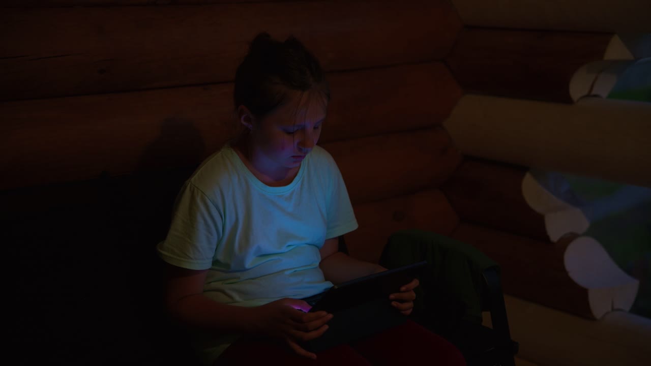 Young Girl Using Digital Tablet in a Dark Wooden Room