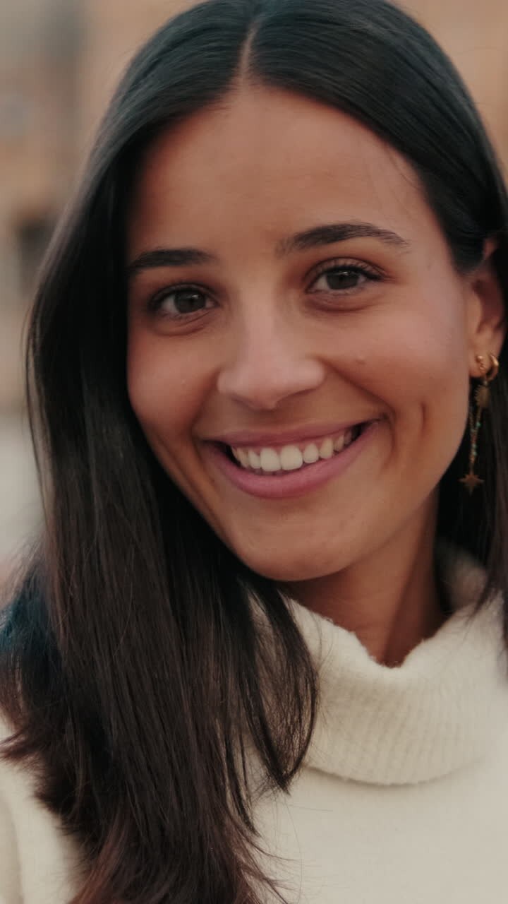 Close-up of young woman turning her head and looking at camera with smile on old