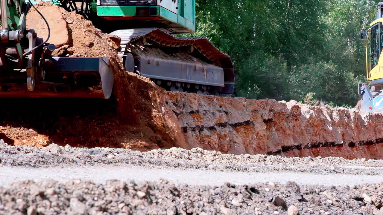 Excavator pushing dirt across open worksite during active earthmoving operations