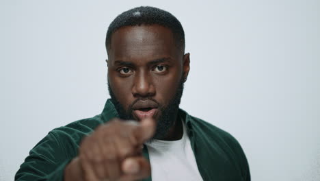 portrait of serious african american man pointing finger on light background.