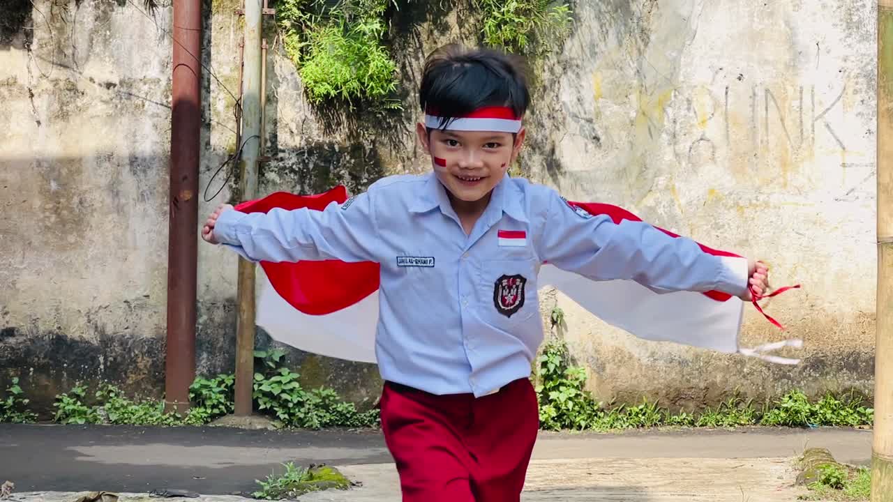 Slow motion of young elementary schoolboy running while waving Indonesian flag, celebrating independence day