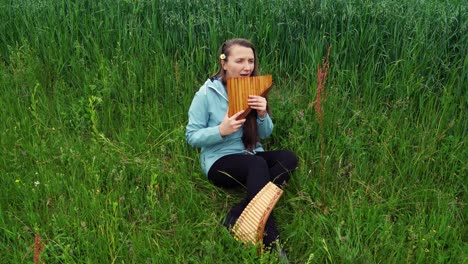 Eine-Junge-Frau-Sitzt-Im-Gras-Und-Spielt-Panflöte