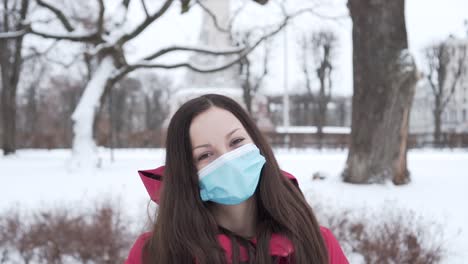 Dama-Con-Mascarilla-Quirúrgica-Sonriendo-Durante-Un-Feliz-Día-De-Caminata-En-El-Parque-De-Invierno