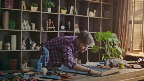 fabricante de cuero poniendo un rollo de cuero en la mesa. propietario de una pequeña empresa