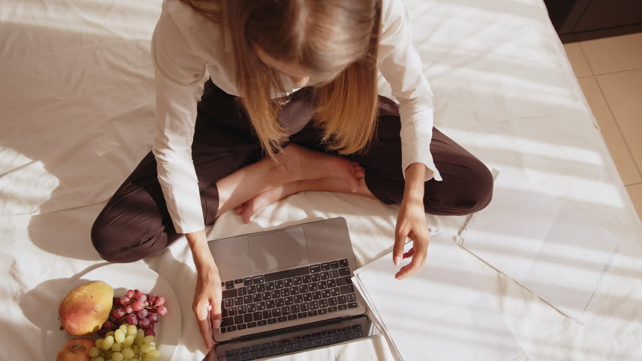 mujer trabajando cómodamente en la computadora portátil en la cama