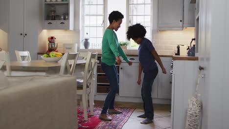 mixed race female couple and daughter dancing in kitchen