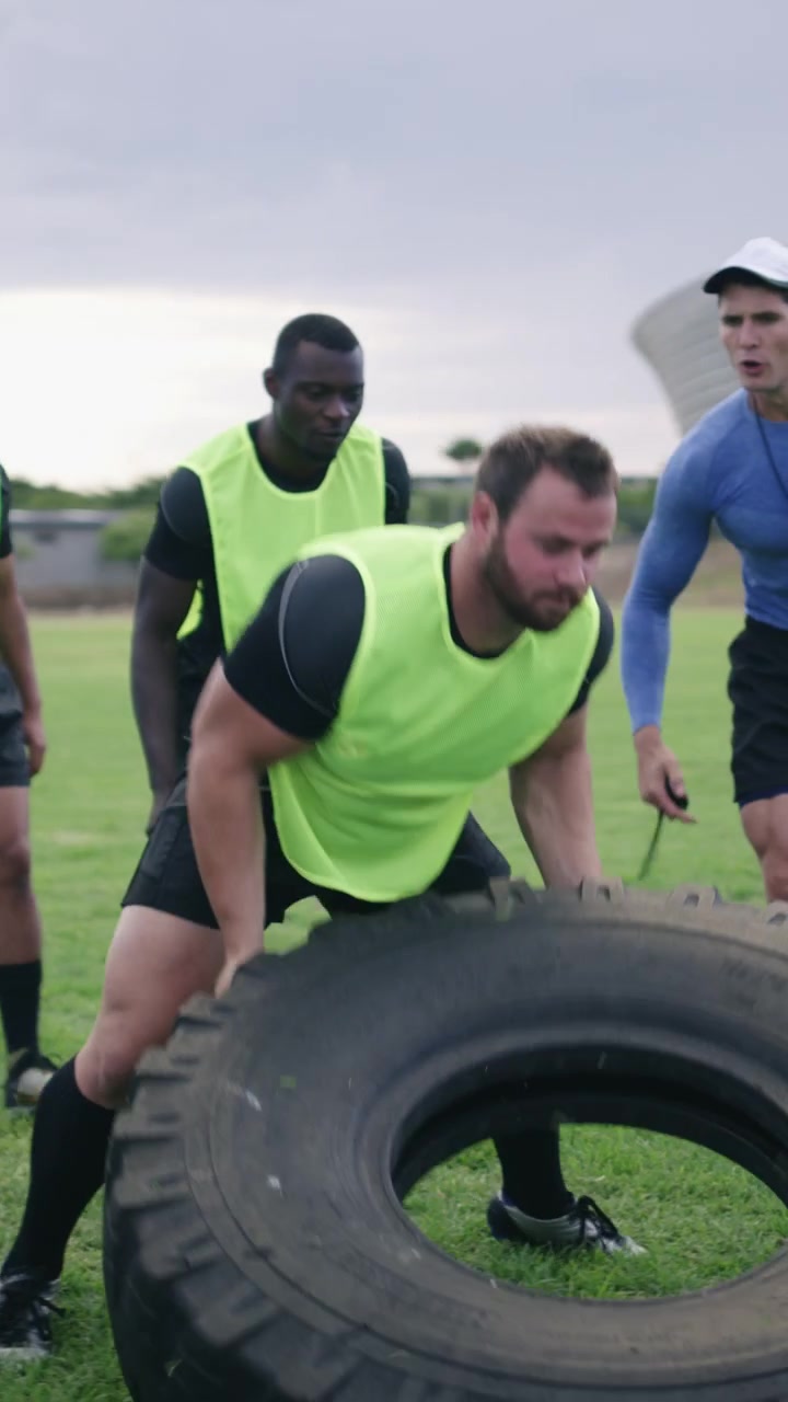 Giocatori di rugby che eseguono esercizi di ribaltamento pneumatici durante un allenamento all'aperto