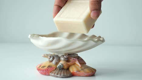 hand holding soap over a decorative seashell soap dish