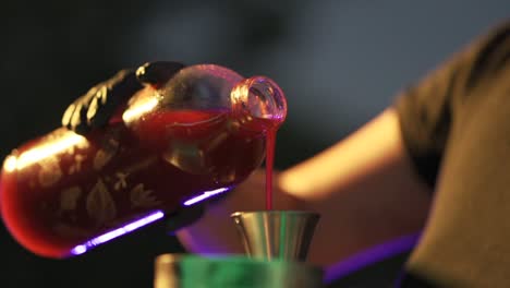 close-up hands of waitress pours juice into measuring cup preparing cocktail recipe