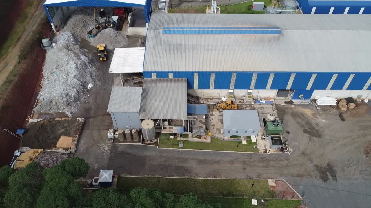 perspectiva a vista de pájaro: avión no tripulado volando, acercándose y revelando las vastas operaciones del almacén de la fábrica