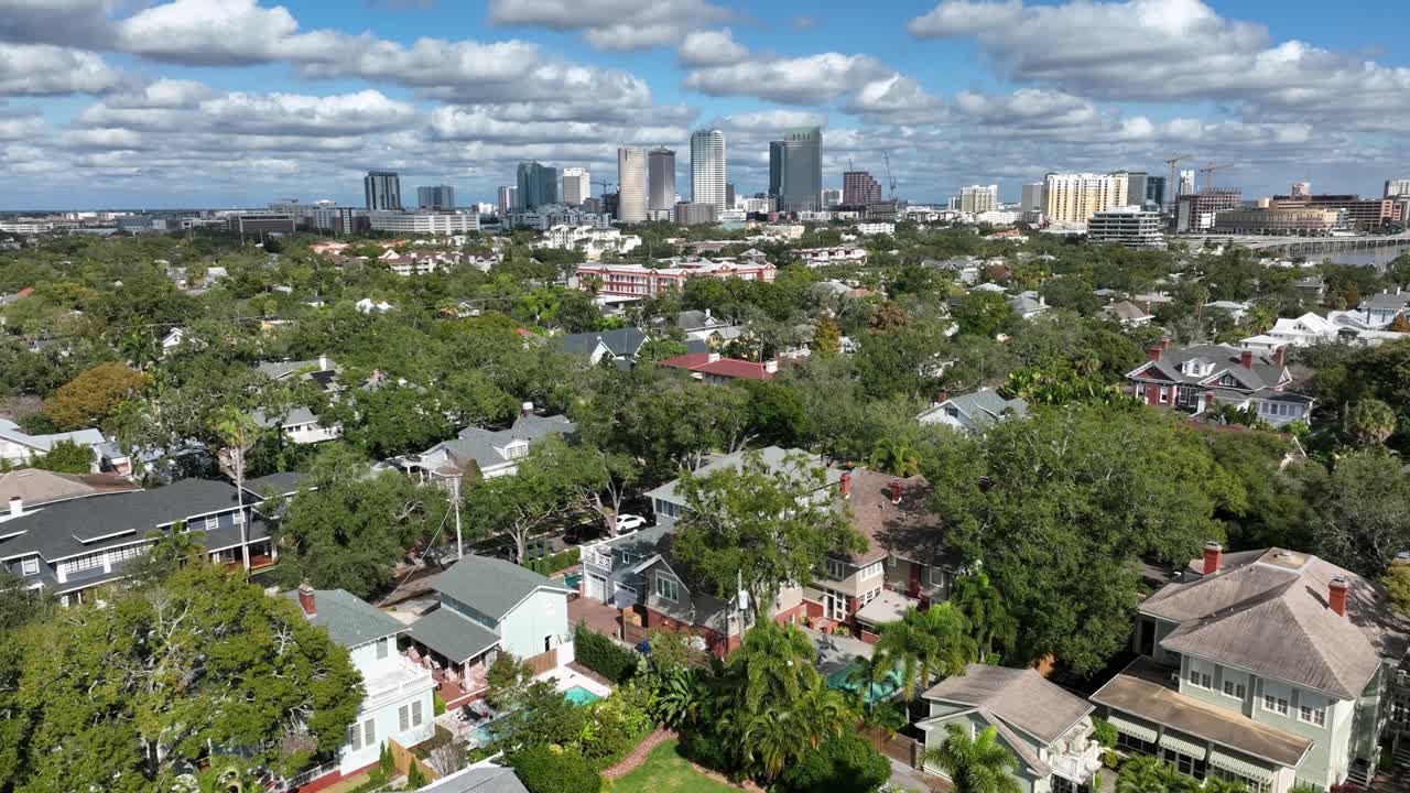 Vista de drone do Hyde Park em Tampa, Flórida, mostrando casas residenciais, cobertura de árvores verdes e horizonte do centro da cidade ao longe em uma cena diurna clara nos Estados Unidos. Plano geral