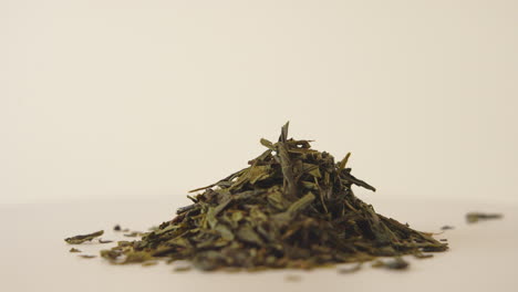 close-up shot of a pile of dried green tea leaves rotating on bright background