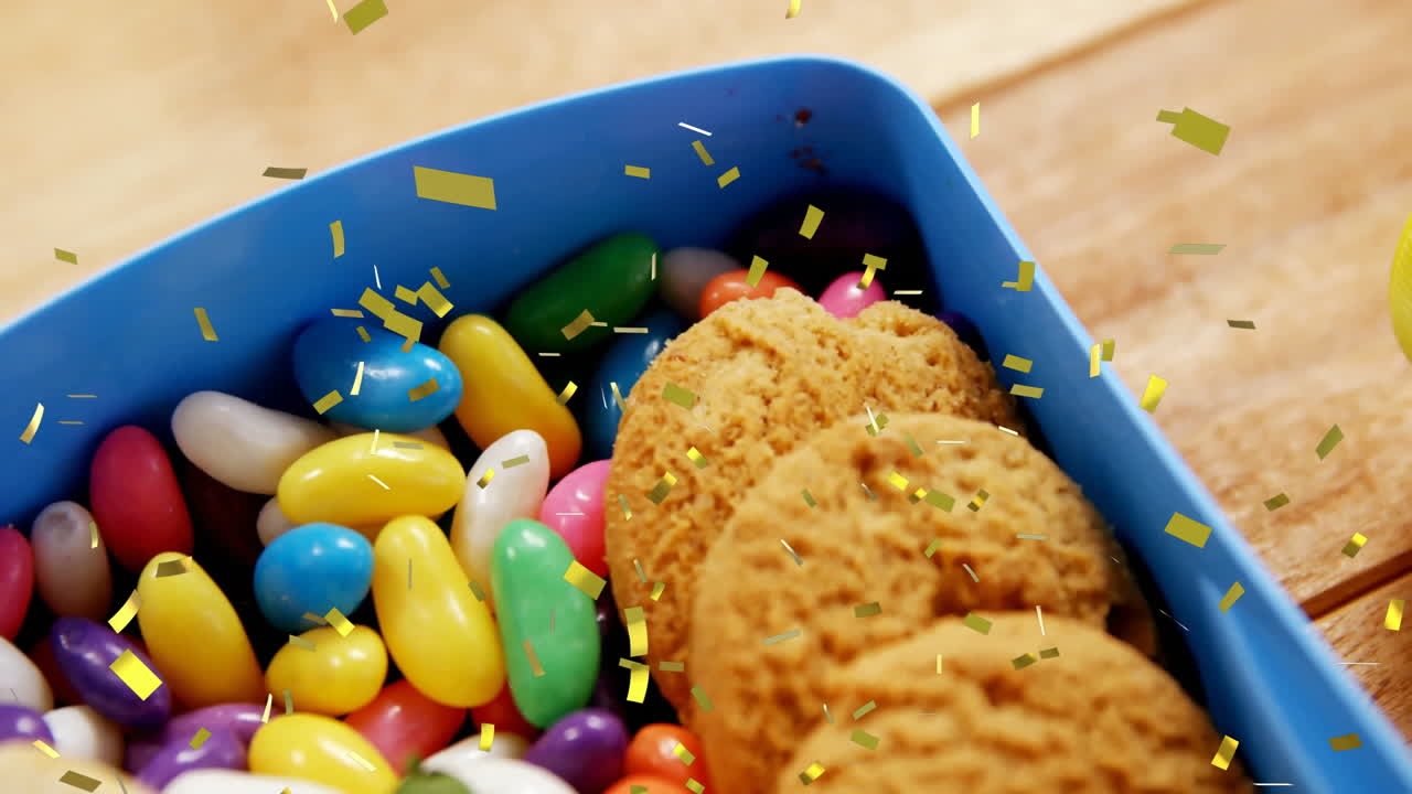 Colorful jelly beans and cookies in blue container with gold confetti animation