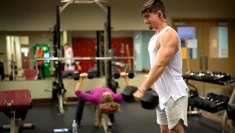 young bodybuilder using a heavy dumbbell doing front alternating dumbbell raises